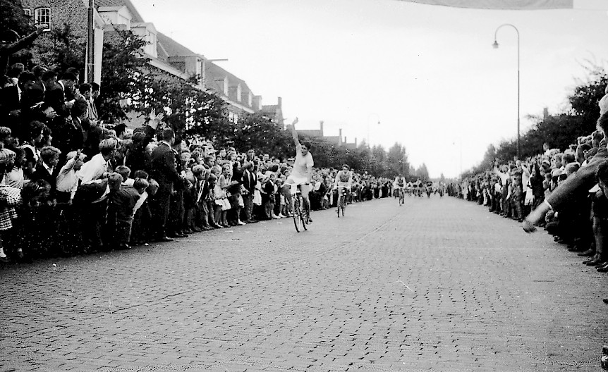 Tijdens deze Tour de Gheel deed vooral Jan Tol ‘Jobse’ van zich spreken. Hij reed een ijzersterke ronde en won zeker twee etappes. Hier gooit hij zijn ene arm in de lucht als hij als eerste over de eindstreep gaat. Gerrit Koning volgt op enkele meters. Door een verrassende ontknoping in de laatste etappe moest hij de eer aan Cor Jonk laten. Let ook op de enorme mensenmassa langs het parcours!