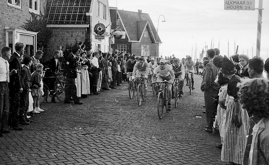 Kees Mooijer ‘Schimmel’ dendert als eerste van een kopgroep over de kasseien van de dijk nabij bar De Molen. Achter hem zien we links Gerrit Koning ‘Keessieman’ en rechts Gerrit Veerman ‘Reus’.